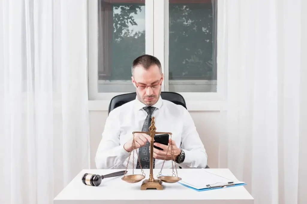 Attorney reviewing case details on smartphone with scales of justice on desk, representing family law appeals in East Cesar Chavez.