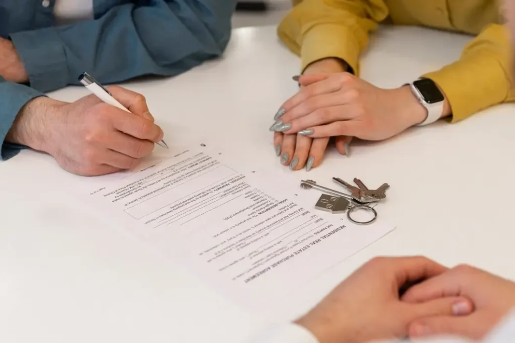 Person signing legal documents related to family law appeals, with keys and another person's hands visible, symbolizing the collaborative nature of the appeals process in Irving, Texas.