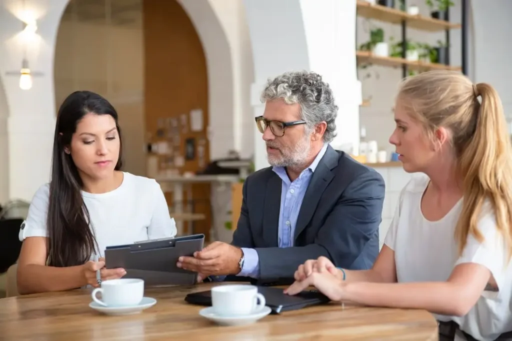 Lawyer consulting with two women at a table, discussing family law appeal options in a modern office setting, with coffee cups and a tablet present.