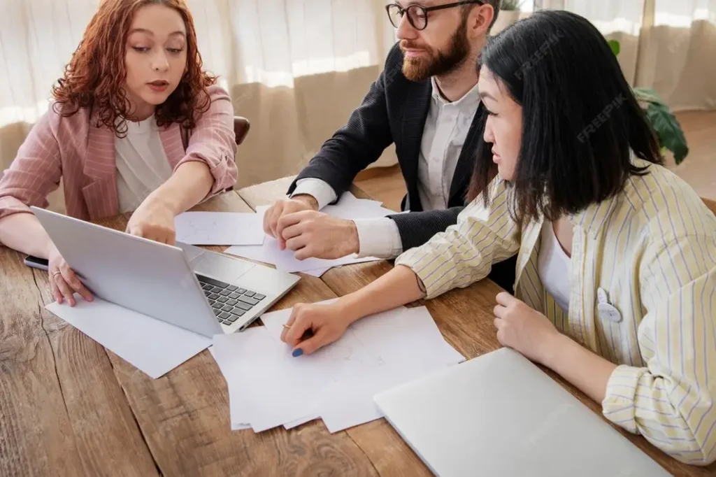 Group of three professionals discussing family law appeals, analyzing documents and using a laptop in a collaborative office setting.