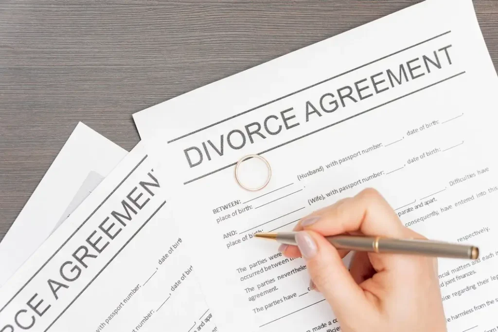Divorce agreement documents with a wedding ring and a hand holding a pen, symbolizing family law appeals and legal processes in River Oaks.