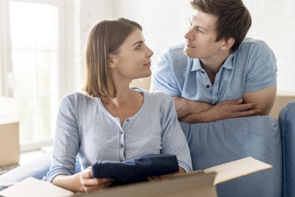Couple looking at each other while packing boxes for moving, symbolizing transitions in relationships related to family law and spousal support appeals.