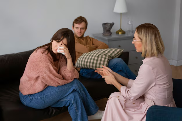 Woman crying on couch with tissue, man sitting behind her, and therapist discussing family issues in a counseling session, highlighting emotional support in family law appeals.