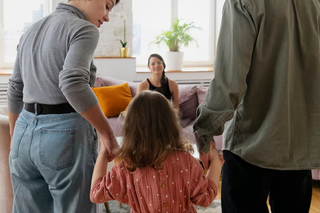 Family interaction with a child holding hands, seated woman in background, emphasizing family law and custody considerations.