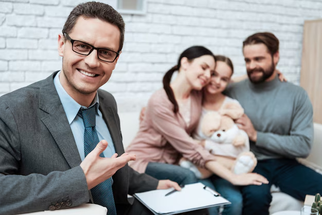 Smiling attorney in a suit gesturing towards a family with a child and a teddy bear, illustrating family law support and consultation in St. Hedwig, Texas.