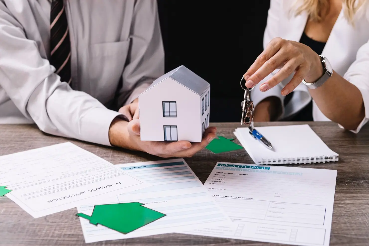 Man and woman discussing property division, holding a model house and keys, with mortgage application documents on the table, symbolizing Texas divorce property appeals.