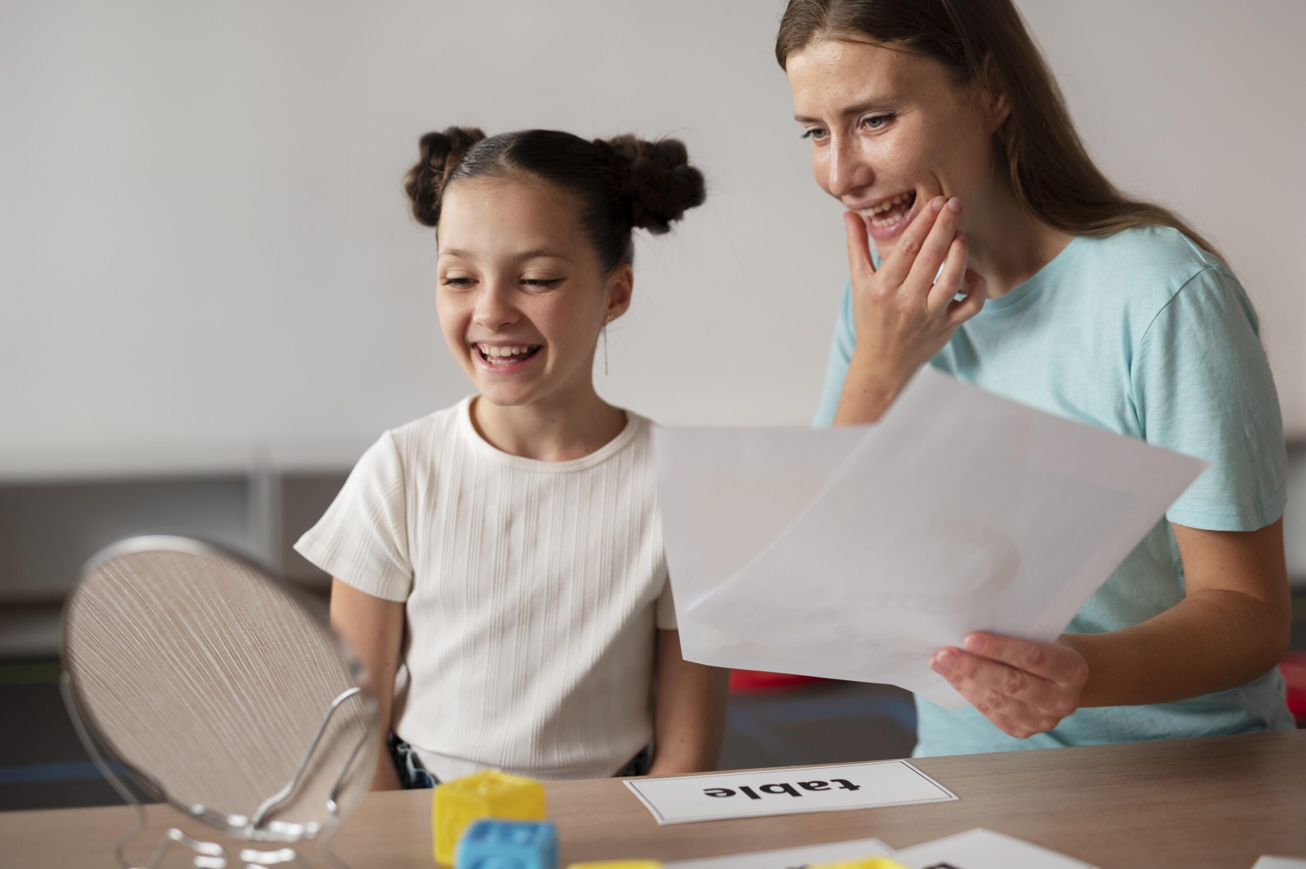 Child and psychologist engaging in speech therapy session, smiling and interacting with educational materials, emphasizing child support and developmental needs.