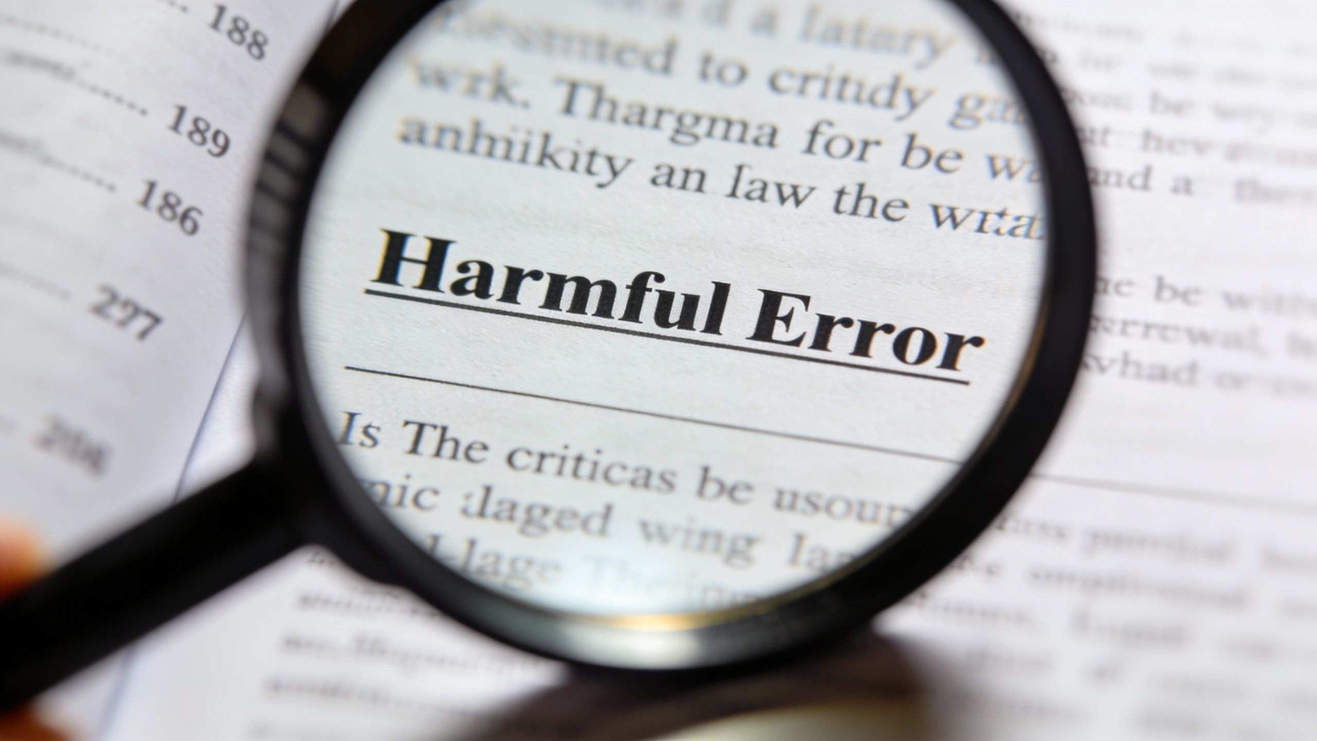 A magnifying glass focused on the words Harmful Error written on a page of a book.