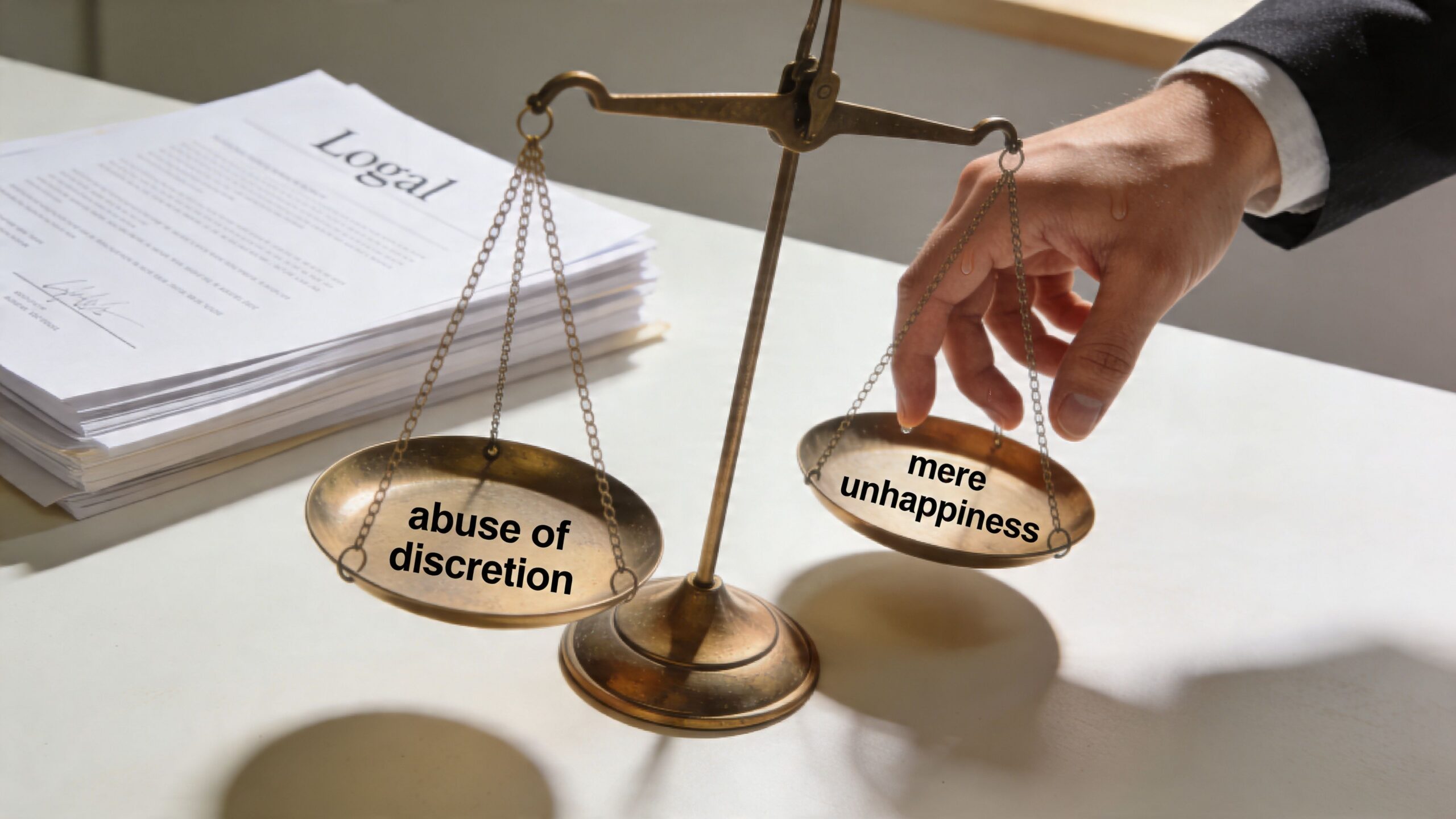 A legal scale weighing the concepts of abuse of discretion versus mere unhappiness in a divorce case.